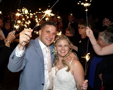 A man and woman holding sparklers in front of people.