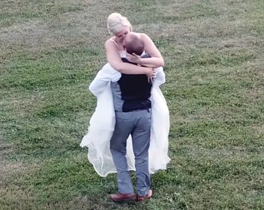 A man and woman hugging in the grass.
