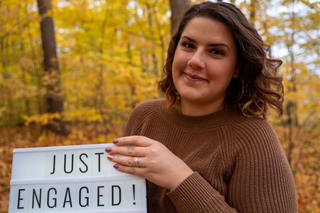 A woman holding a sign that says " just engaged ".